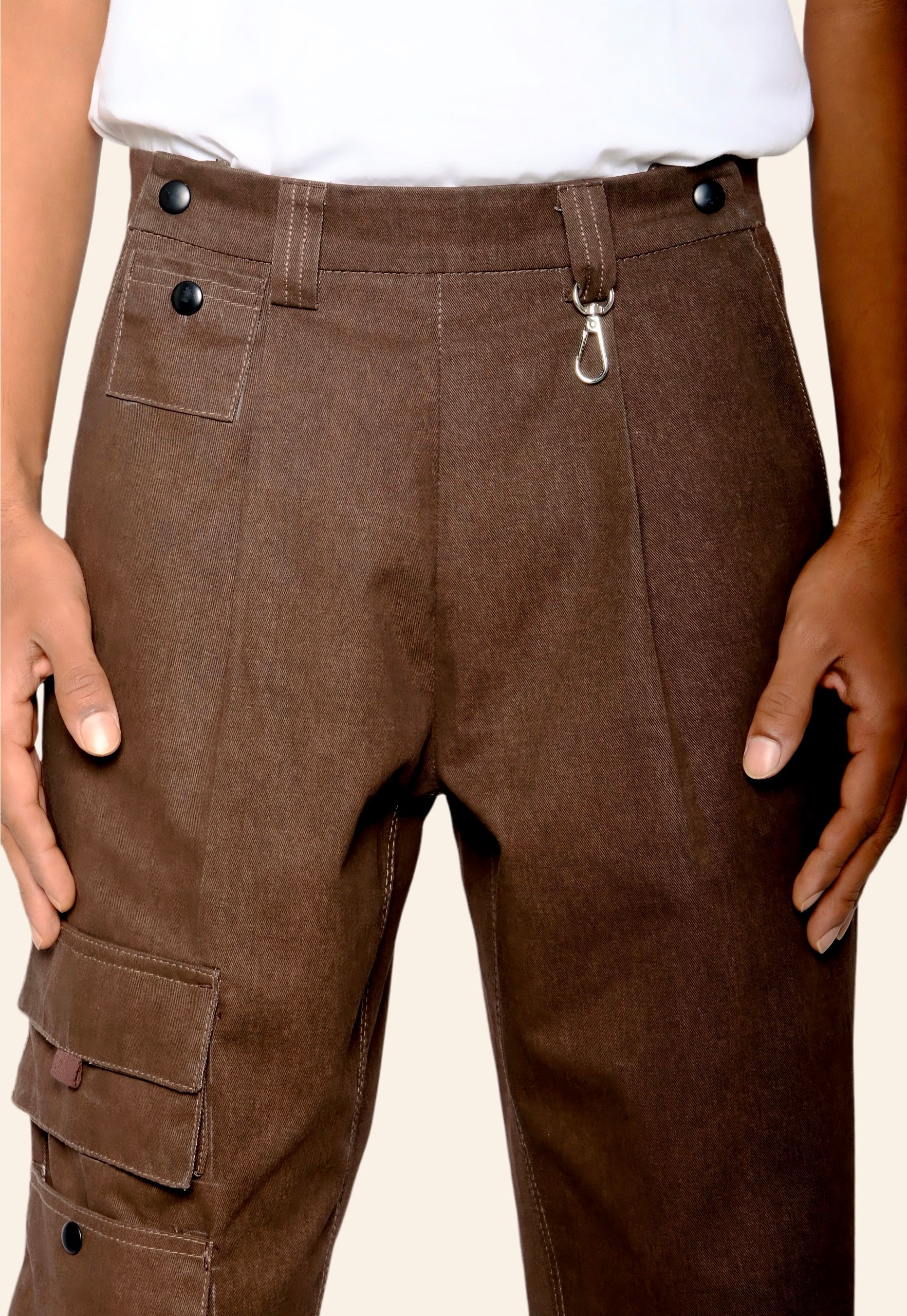 Brown cargo pants with buttons and a hook on a beige background