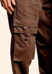Close-up of brown cargo pants with multiple pockets on a beige background